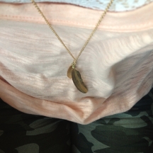 gold feather necklace, white lace bralet, coral tee, camo denim